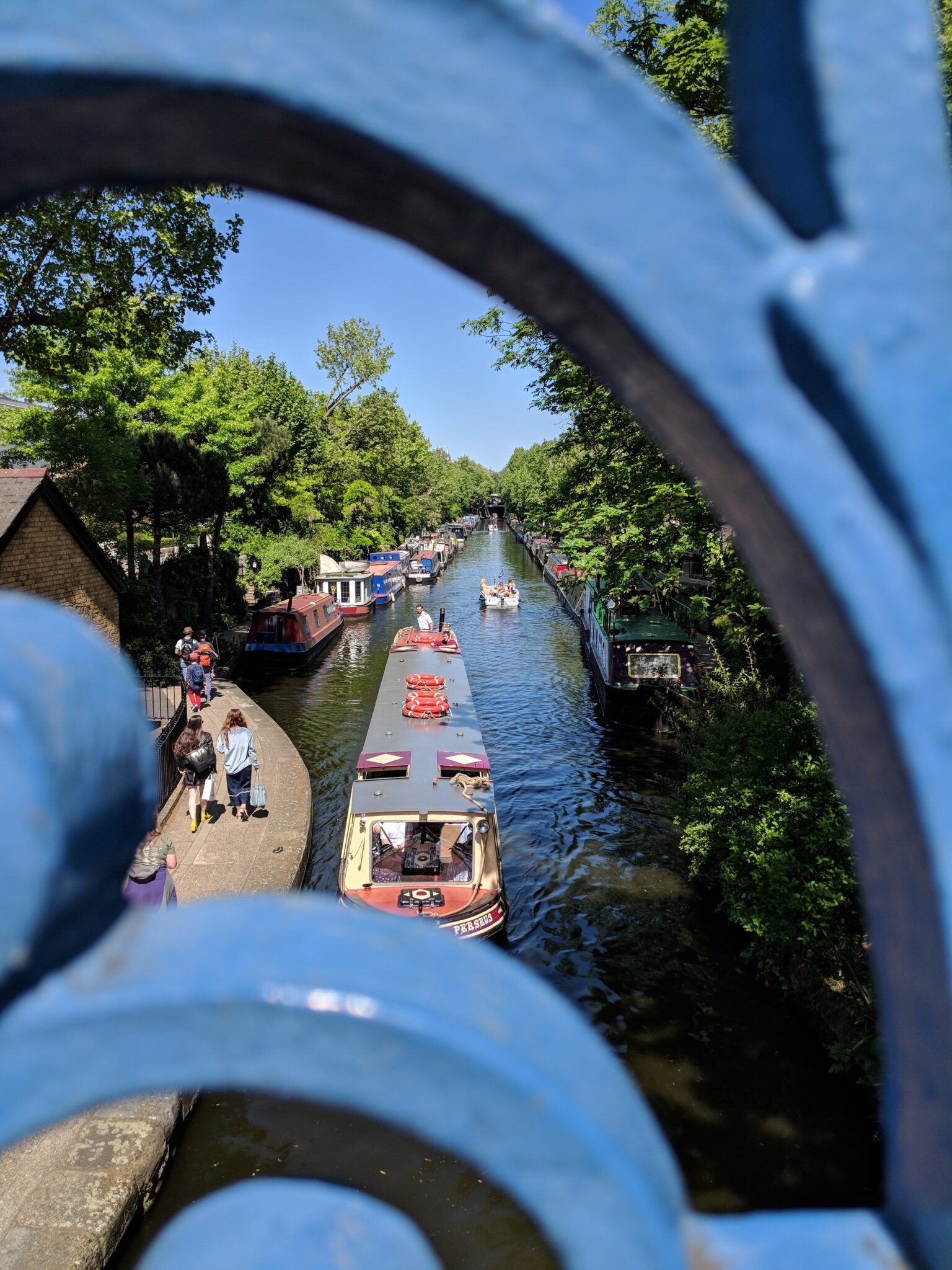 Canal boats viewed through blue railings in Little Venice